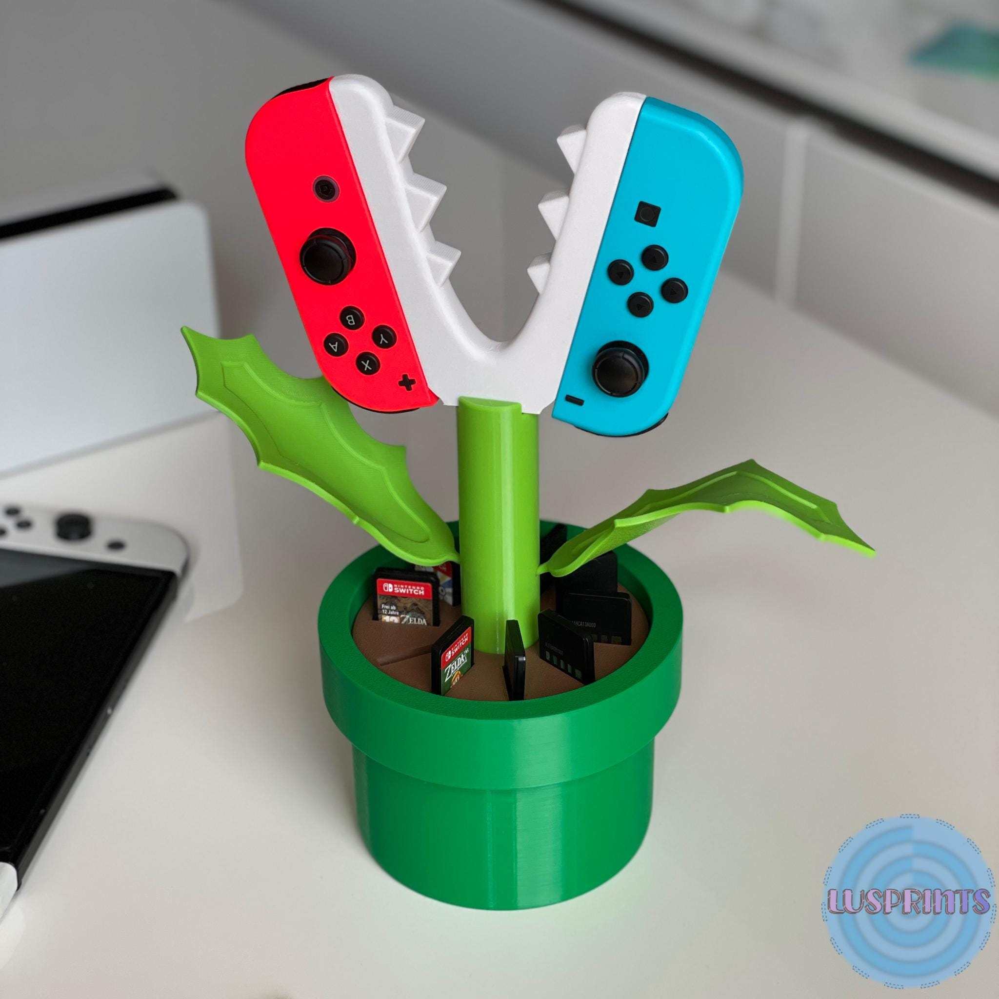 Retro Piranha Plant Joy-Con Halter als Schreibtisch-Deko neben einem Monitor im Gaming-Zimmer.