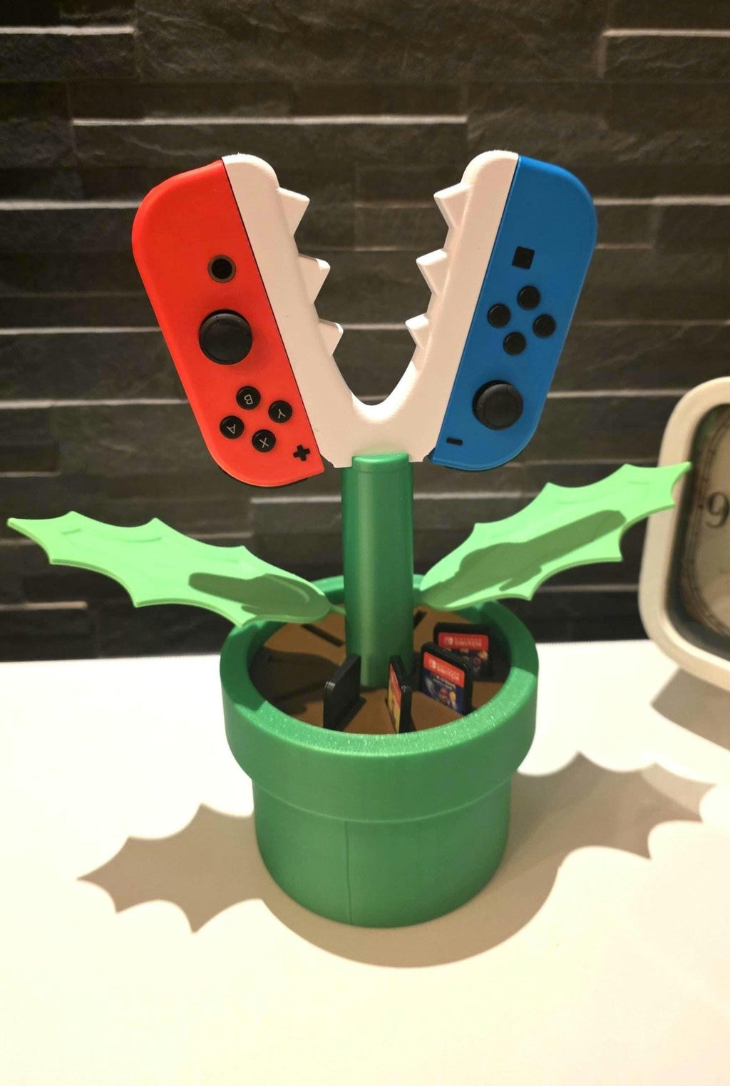 Nahaufnahme der integrierten Slots im grünen Topf für bis zu 10 Nintendo Switch Spielekarten.